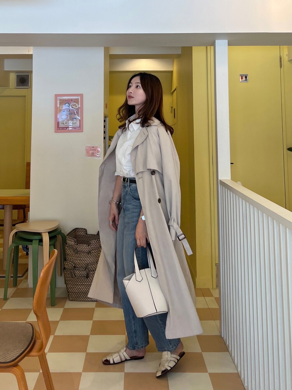 ベージュ系のトレンチコート、ホワイト系のハンドバッグ、ホワイト系のサンダルを着用したレディースの春コーディネートの2枚目の写真