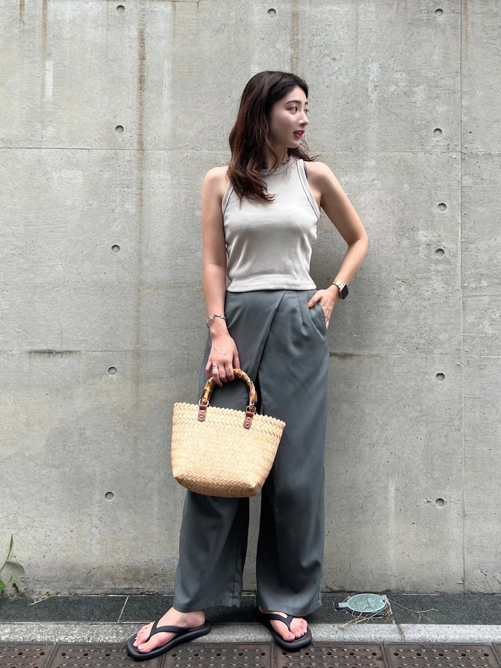 ベージュ系のタンクトップ、グレー系のスラックス、ベージュ系のかごバッグを着用したレディースの夏コーディネートの2枚目の写真