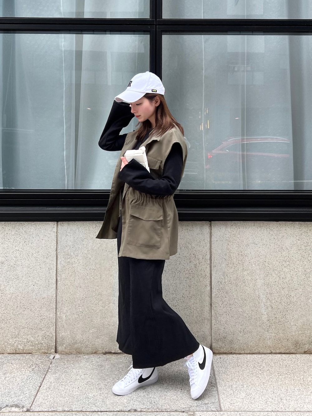 ブラック系のワンピース、グリーン系のベスト、ホワイト系のスニーカーを着用したレディースの春コーディネートの3枚目の写真