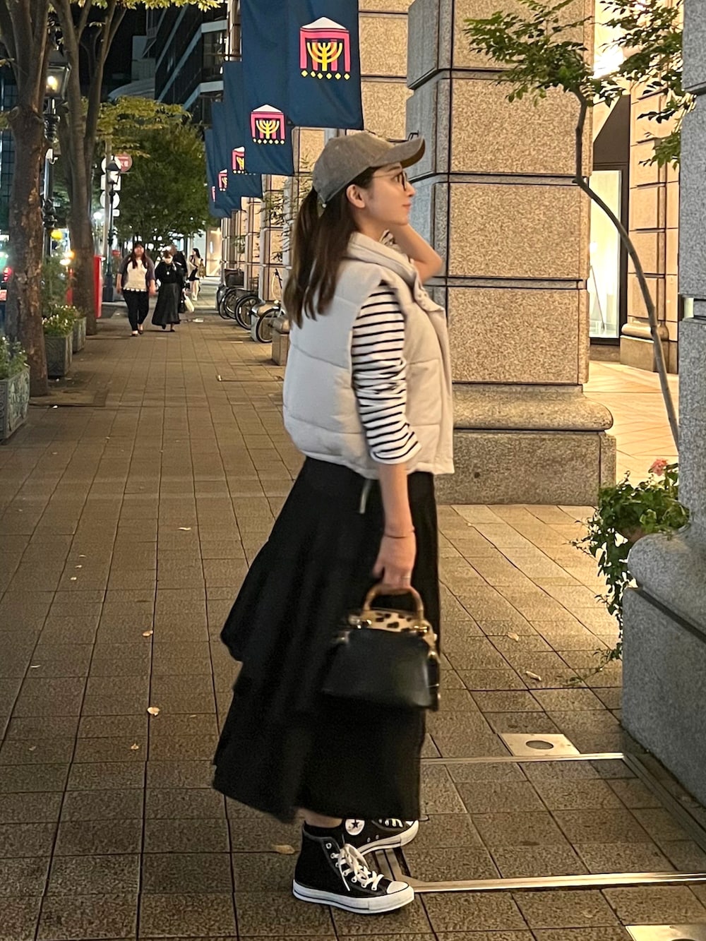 ホワイト系のダウンベスト、ホワイト系のTシャツ/カットソー、ブラック系のスカートを着用したレディースの秋コーディネートの3枚目の写真