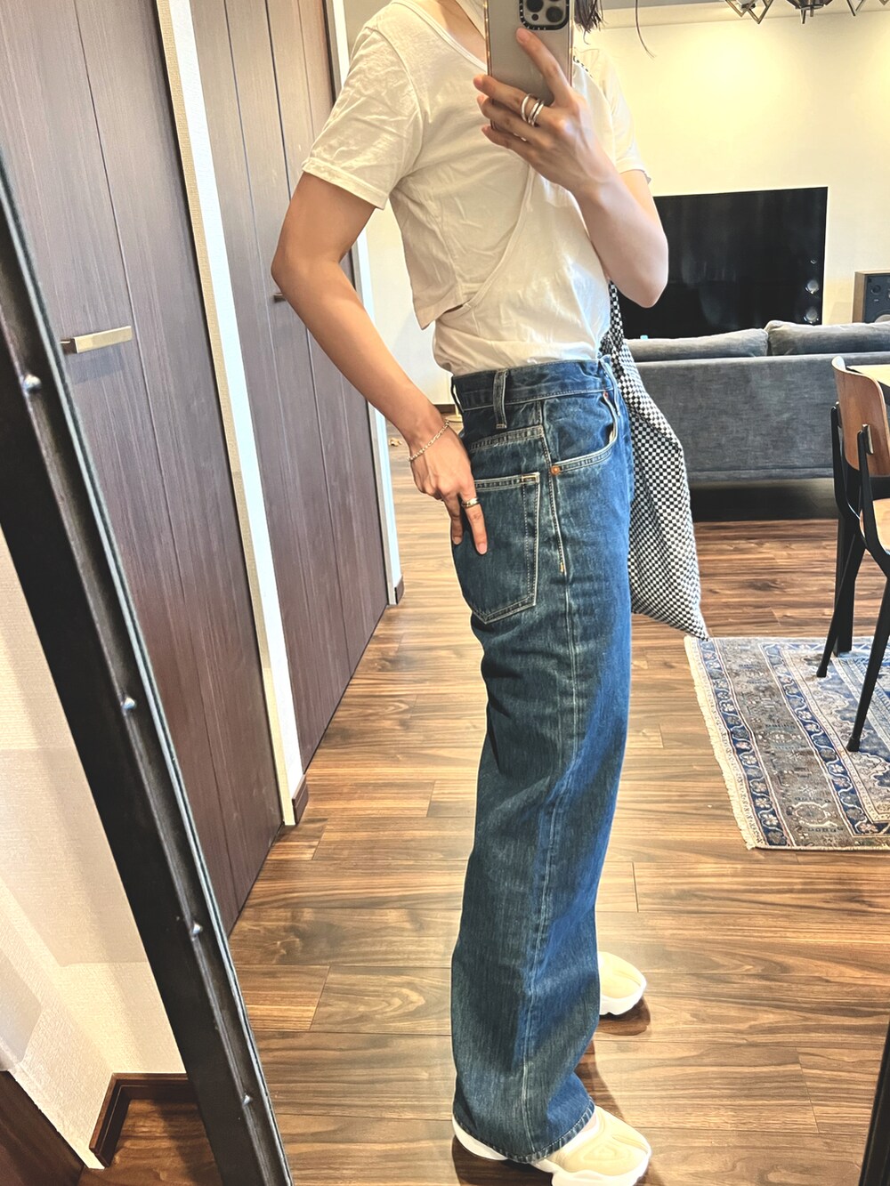 ブルー系のデニムパンツ、ベージュ系のサンダル、ホワイト系のトートバッグを着用したレディースの夏コーディネートの2枚目の写真