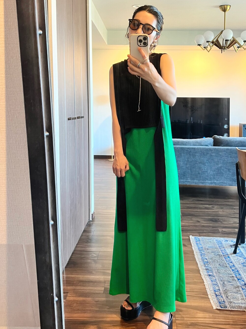 ブラック系のベスト、グリーン系のワンピース、ブラック系のサンダルを着用したレディースの夏コーディネートの2枚目の写真