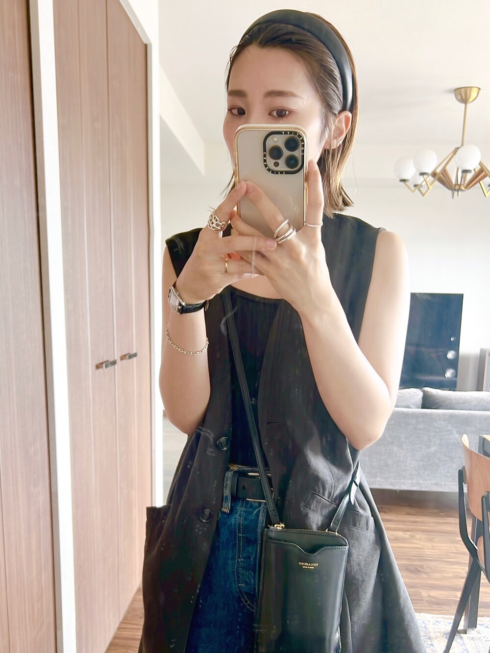 ブラック系のベスト、ブラック系のショルダーバッグ、ブルー系のデニムパンツを着用したレディースの夏コーディネートの3枚目の写真