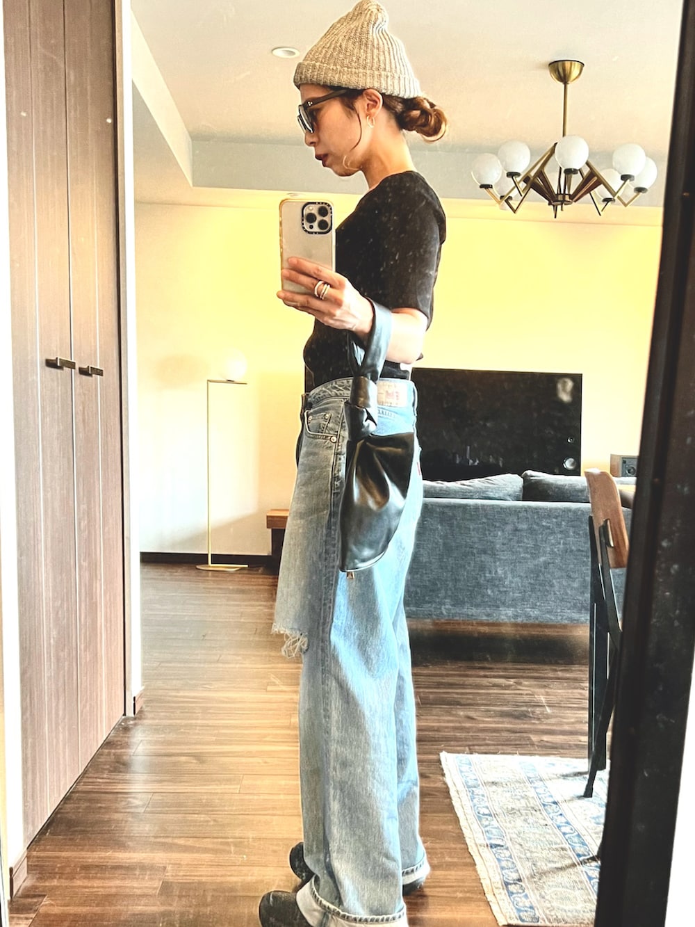 ブルー系のデニムパンツ、ブラック系のTシャツ/カットソー、ブラック系のハンドバッグを着用したレディースの夏コーディネートの2枚目の写真