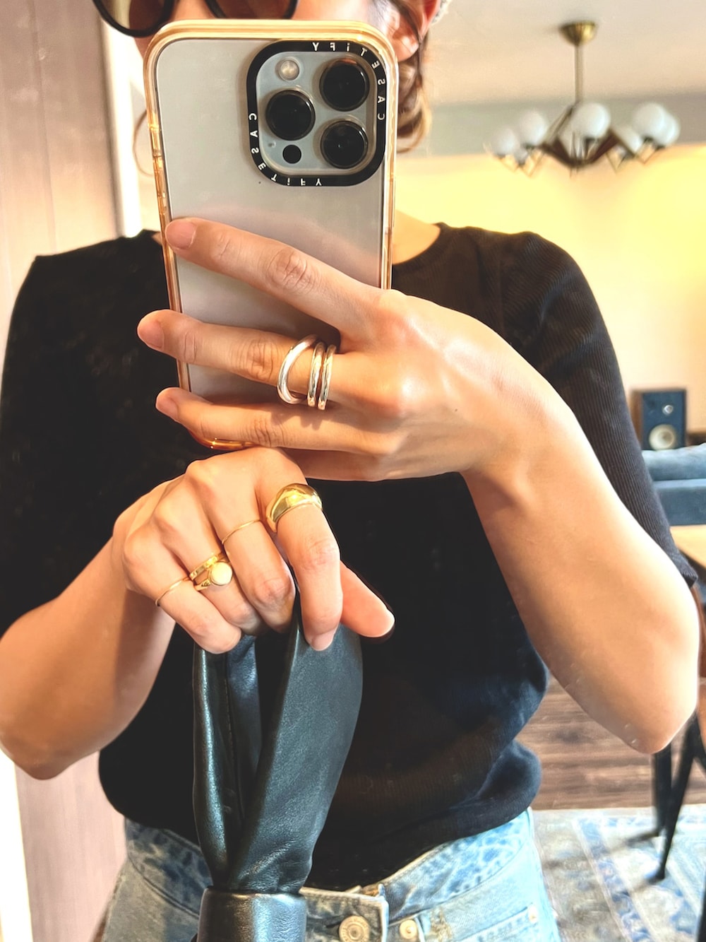 ブルー系のデニムパンツ、ブラック系のTシャツ/カットソー、ブラック系のハンドバッグを着用したレディースの夏コーディネートの4枚目の写真