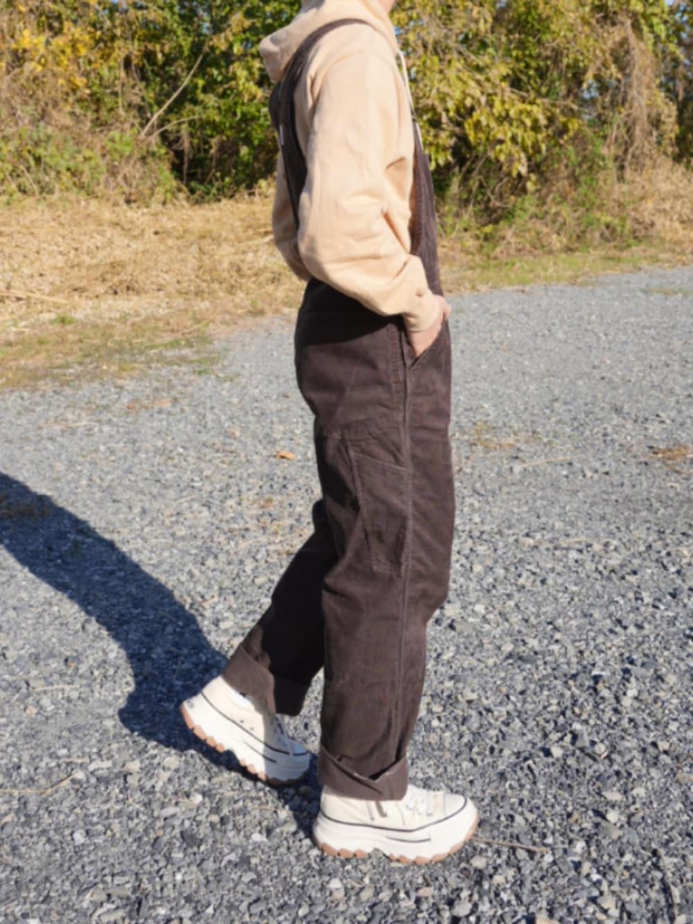 ブラウン系のサロペット/オーバーオール、ベージュ系のスニーカー、ベージュ系のパーカーを着用したメンズの冬コーディネートの3枚目の写真