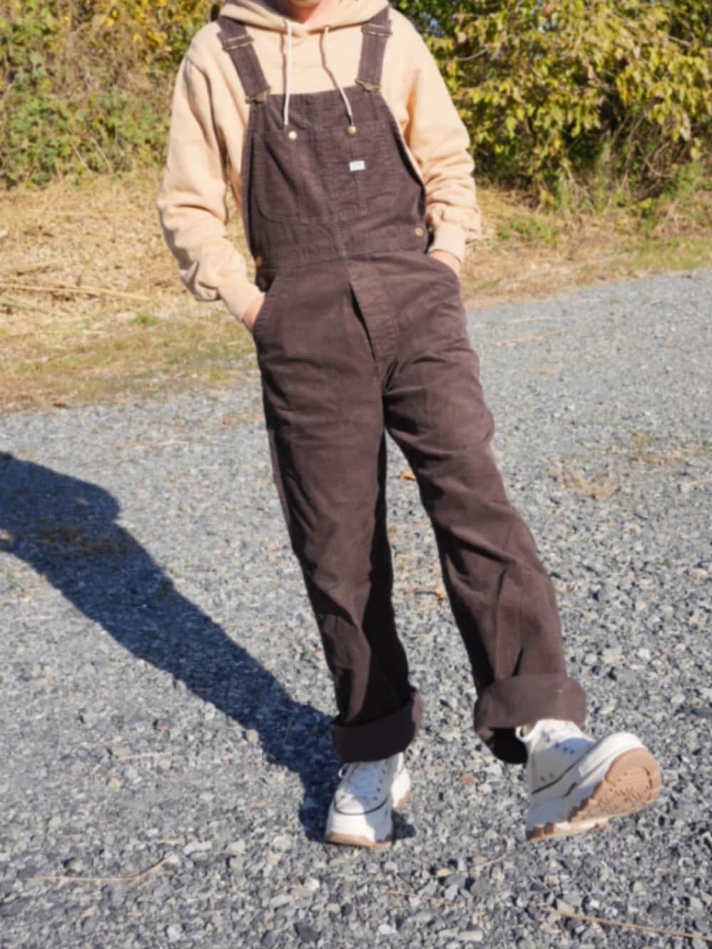 ブラウン系のサロペット/オーバーオール、ベージュ系のスニーカー、ベージュ系のパーカーを着用したメンズの冬コーディネートの2枚目の写真