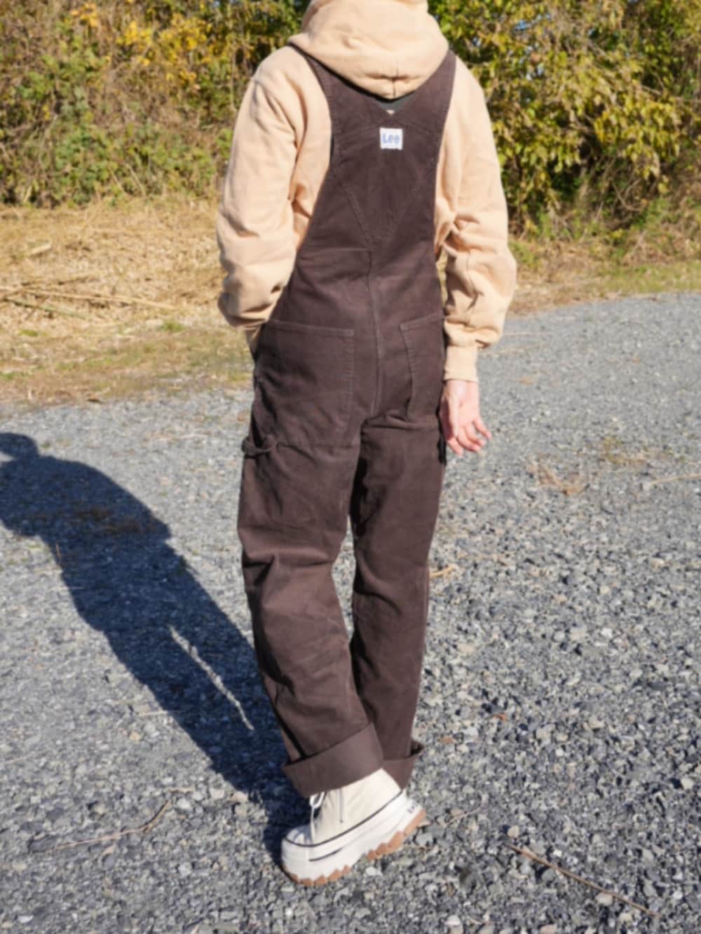 ブラウン系のサロペット/オーバーオール、ベージュ系のスニーカー、ベージュ系のパーカーを着用したメンズの冬コーディネートの4枚目の写真