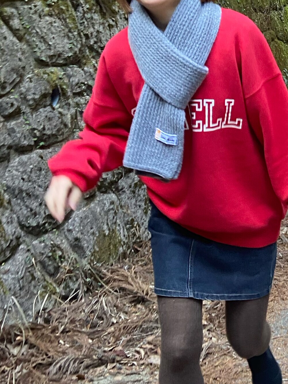 ブラック系のブーツ、ブラック系のデニムスカート、レッド系のスウェットを着用したレディースの冬コーディネートの2枚目の写真