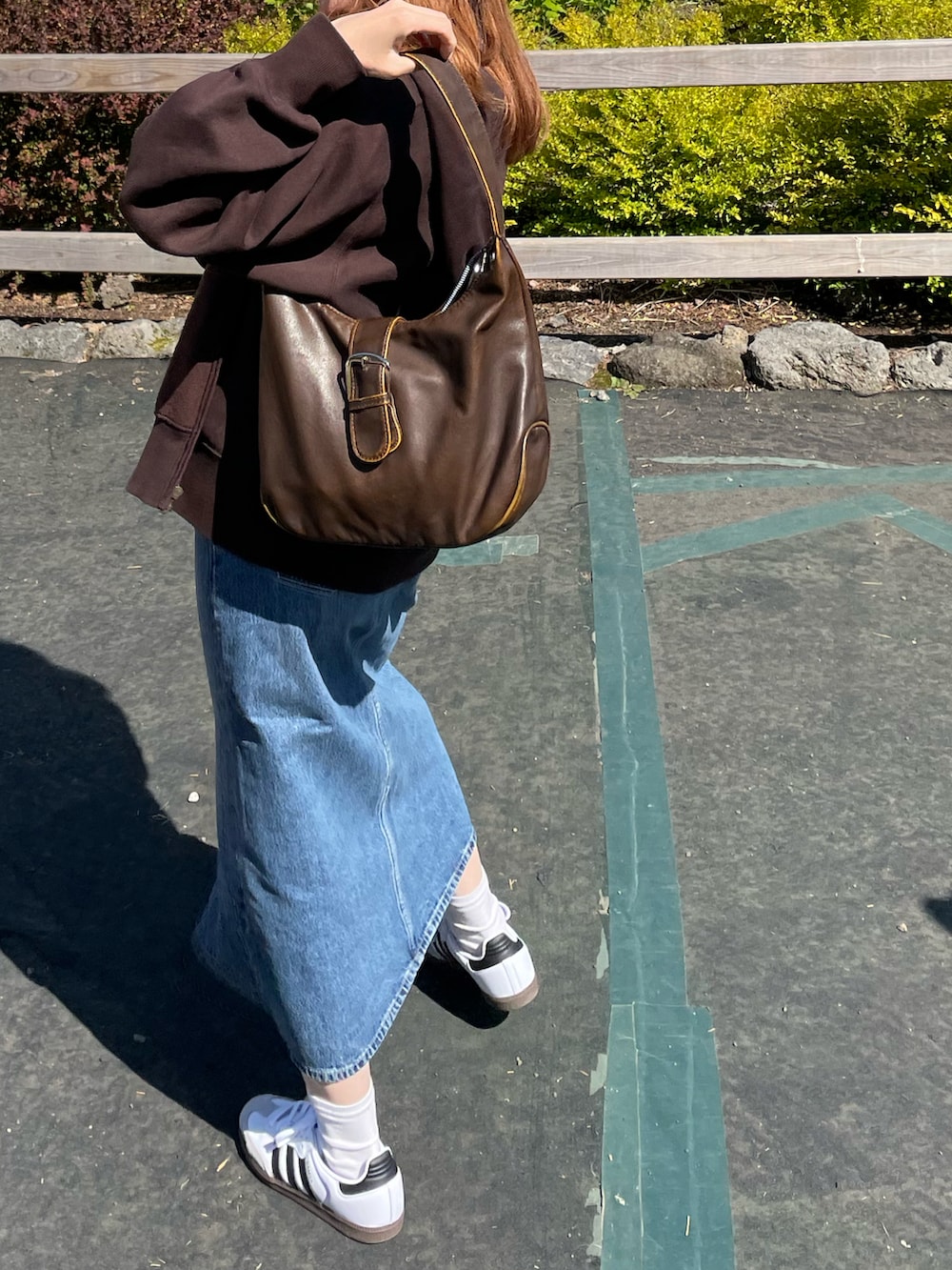 ブルー系のデニムスカート、ホワイト系のスニーカーを着用したレディースの春コーディネートの2枚目の写真