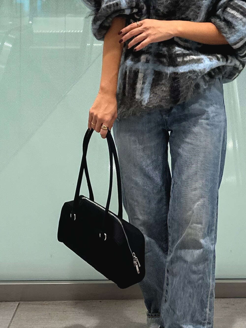 グレー系のニット/セーター、ブルー系のデニムパンツ、ブラック系のハンドバッグを着用したレディースの秋コーディネートの6枚目の写真