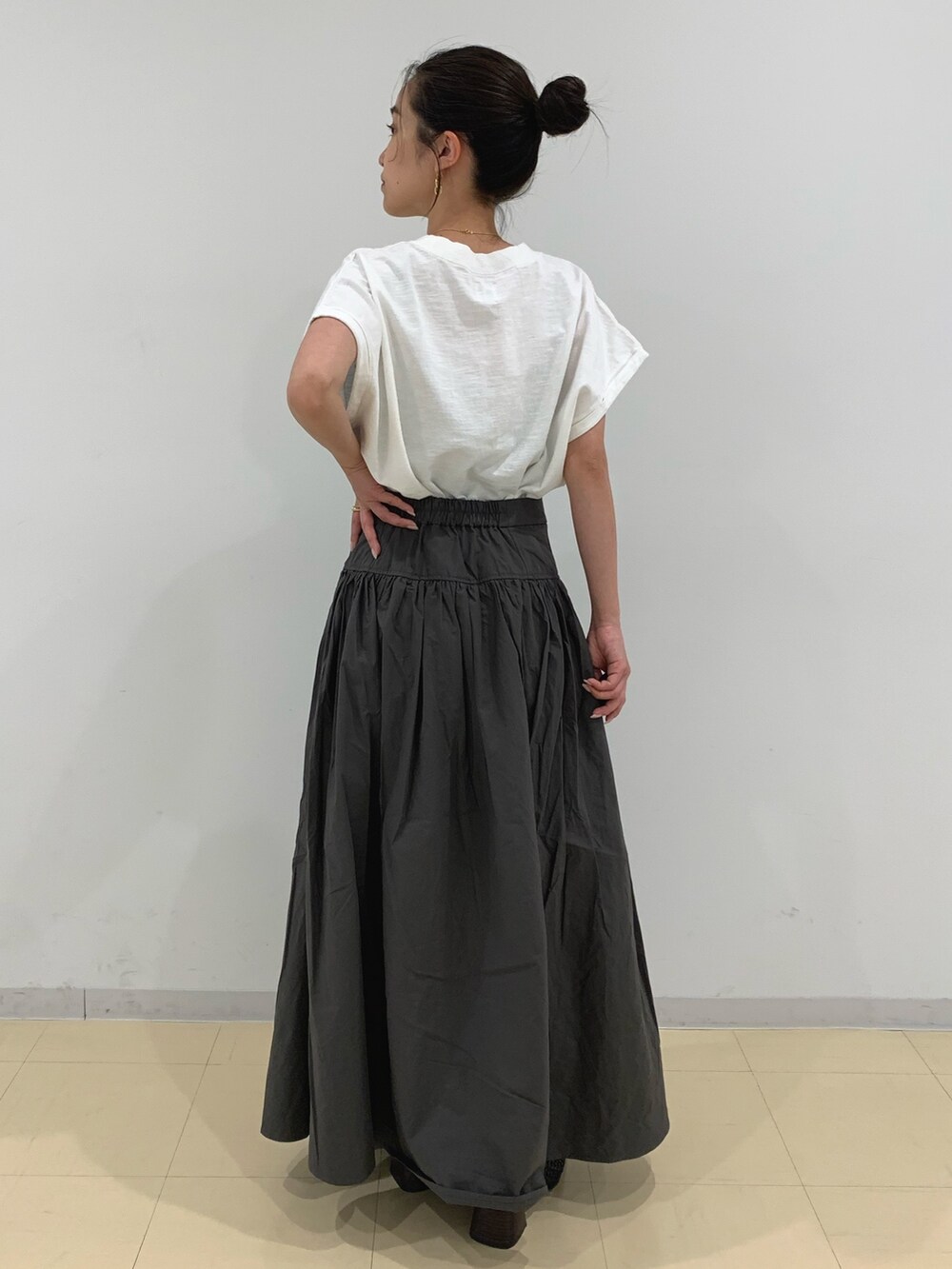 ホワイト系のTシャツ/カットソー、グレー系のスカート、ブラック系のサンダルを着用したレディースの春コーディネートの3枚目の写真