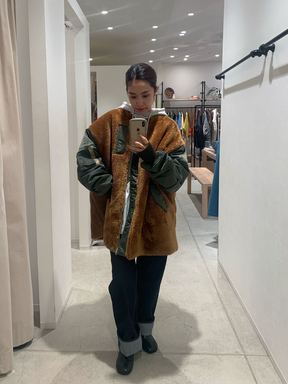 グリーン系のブルゾン、グレー系のパーカー、ブルー系のデニムパンツを着用したレディースの秋コーディネートの3枚目の写真