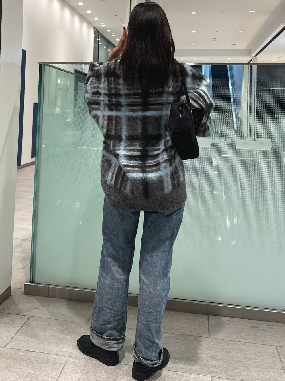 グレー系のニット/セーター、ブルー系のデニムパンツ、ブラック系のハンドバッグを着用したレディースの秋コーディネートの3枚目の写真