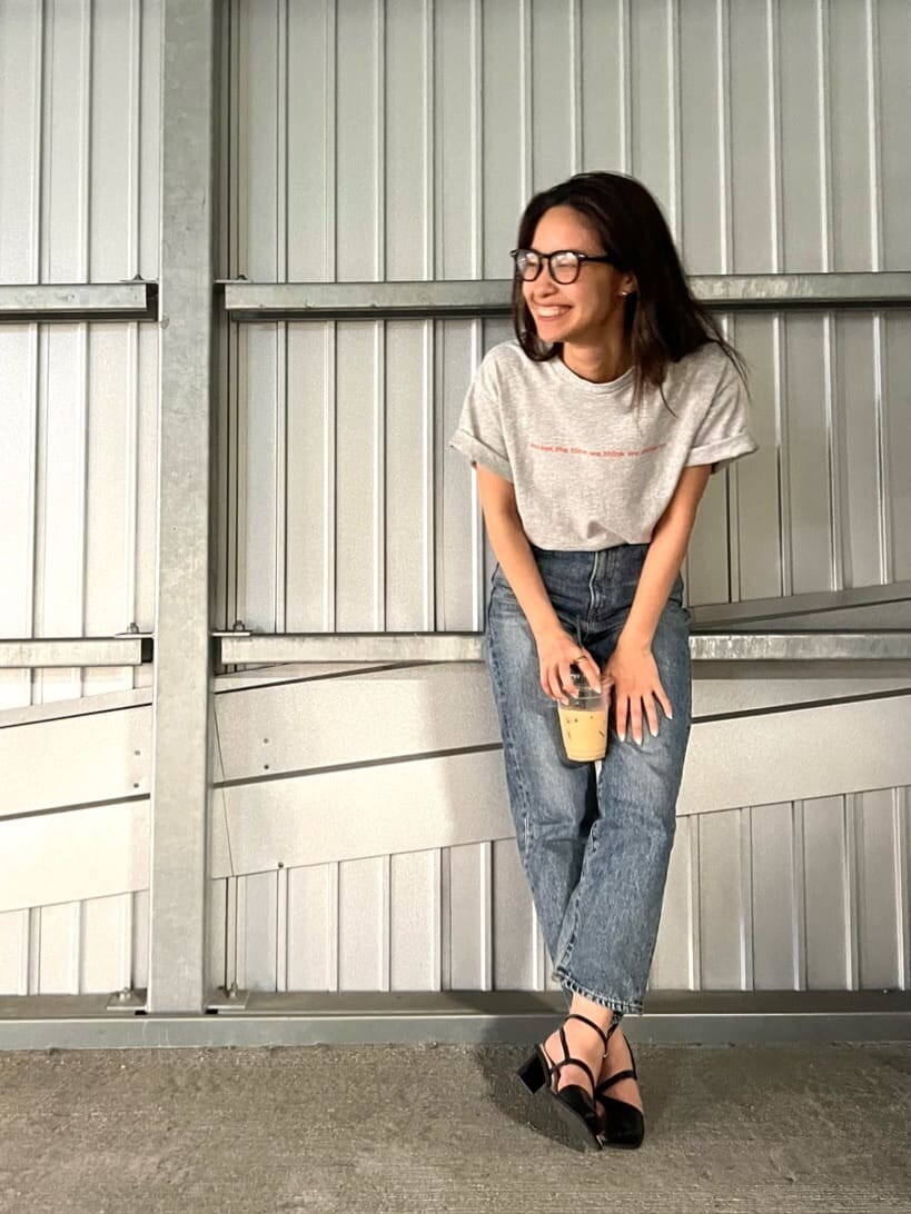 グレー系のTシャツ/カットソー、ブラック系のサンダル、ブルー系のデニムパンツを着用したレディースの春コーディネートの4枚目の写真
