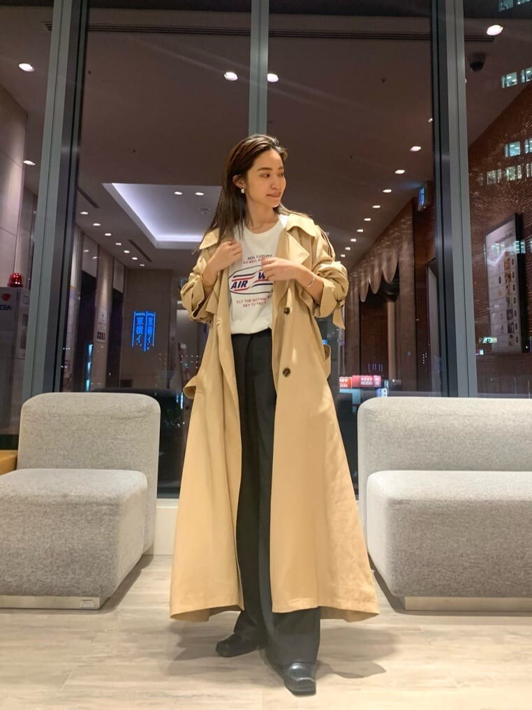 ベージュ系のトレンチコート、グレー系のスラックス、ホワイト系のTシャツ/カットソーを着用したレディースの秋コーディネートの2枚目の写真