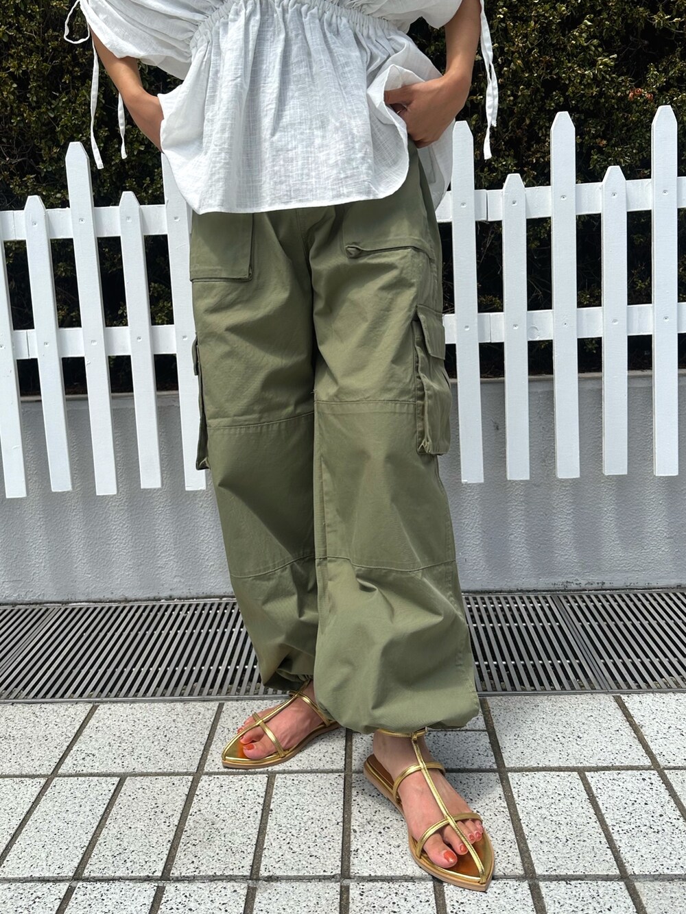 ホワイト系のシャツ/ブラウス、グリーン系のカーゴパンツ、ゴールド系のサンダルを着用したレディースの夏コーディネートの6枚目の写真