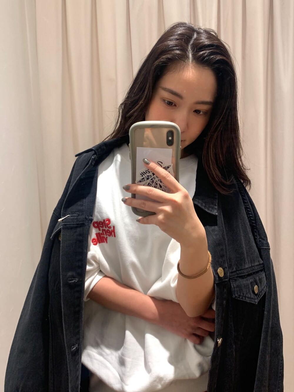 ホワイト系のスウェット、ブラック系のデニムジャケット、オレンジ系のスカートを着用したレディースの冬コーディネートの3枚目の写真