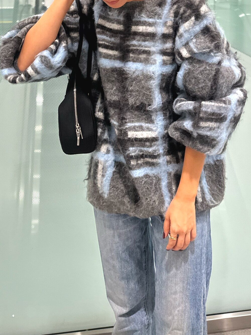 グレー系のニット/セーター、ブルー系のデニムパンツ、ブラック系のハンドバッグを着用したレディースの秋コーディネートの5枚目の写真