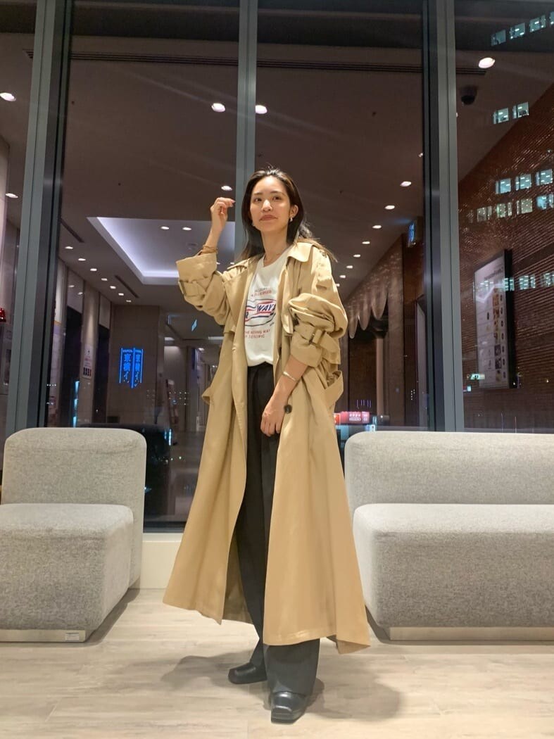 ベージュ系のトレンチコート、グレー系のスラックス、ホワイト系のTシャツ/カットソーを着用したレディースの秋コーディネートの5枚目の写真