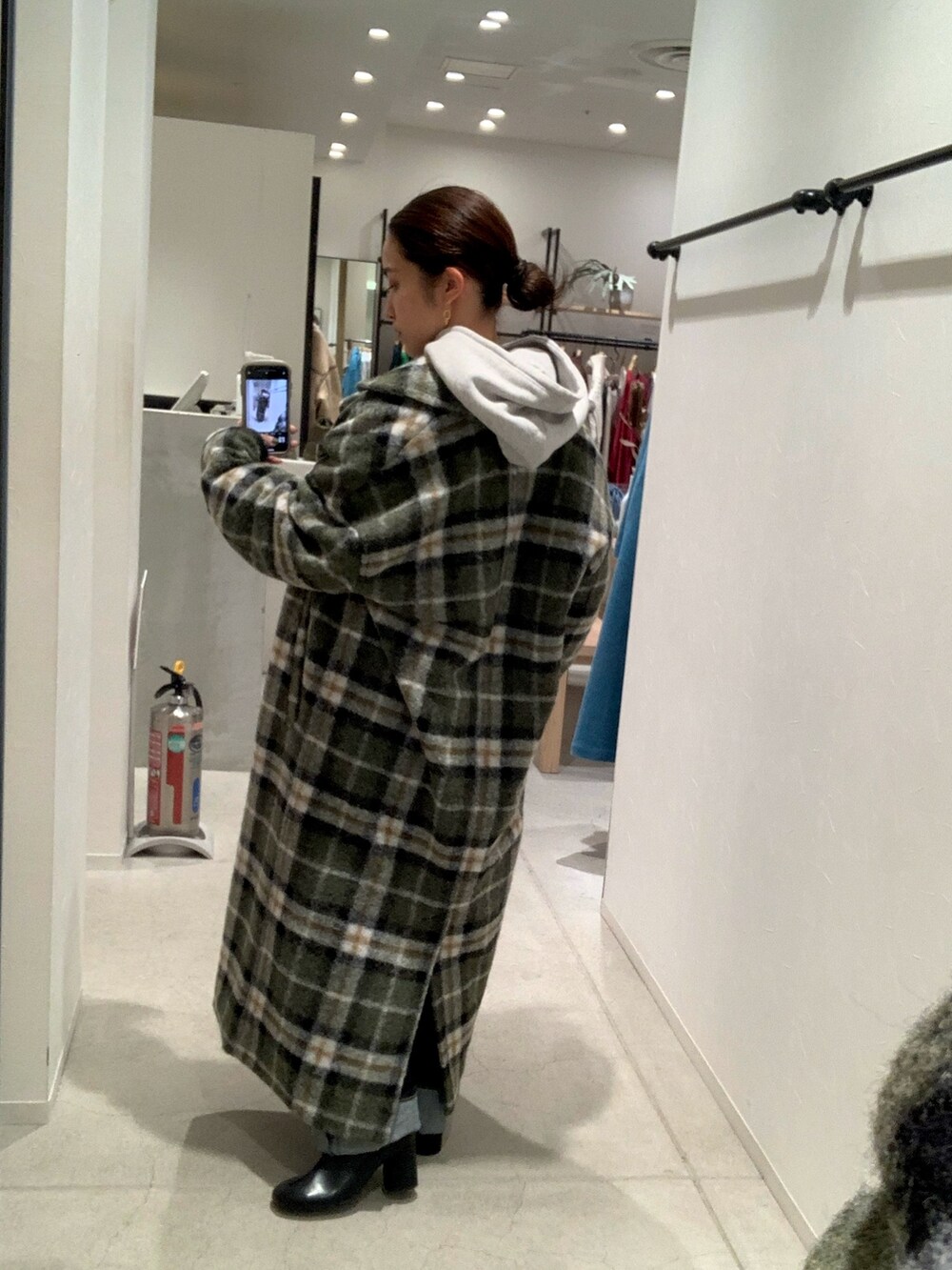 ブルー系のデニムパンツ、その他のチェスターコート、グレー系のパーカーを着用したレディースの秋コーディネートの3枚目の写真