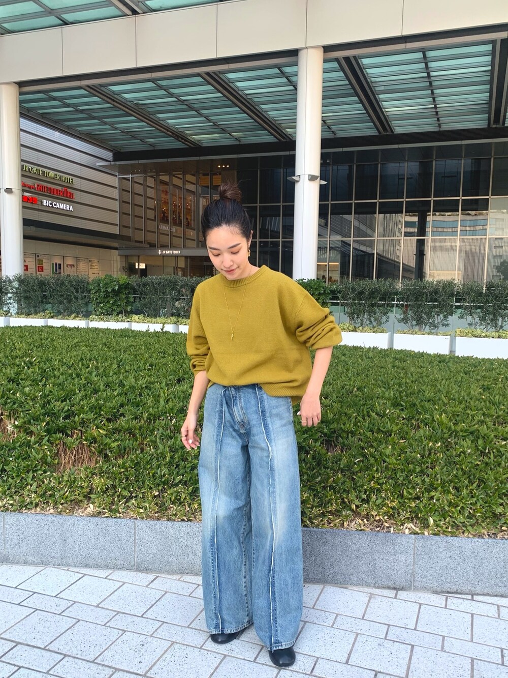 ブラウン系のその他アウター、グリーン系のニット/セーター、ブラック系のブーツを着用したレディースの冬コーディネートの6枚目の写真