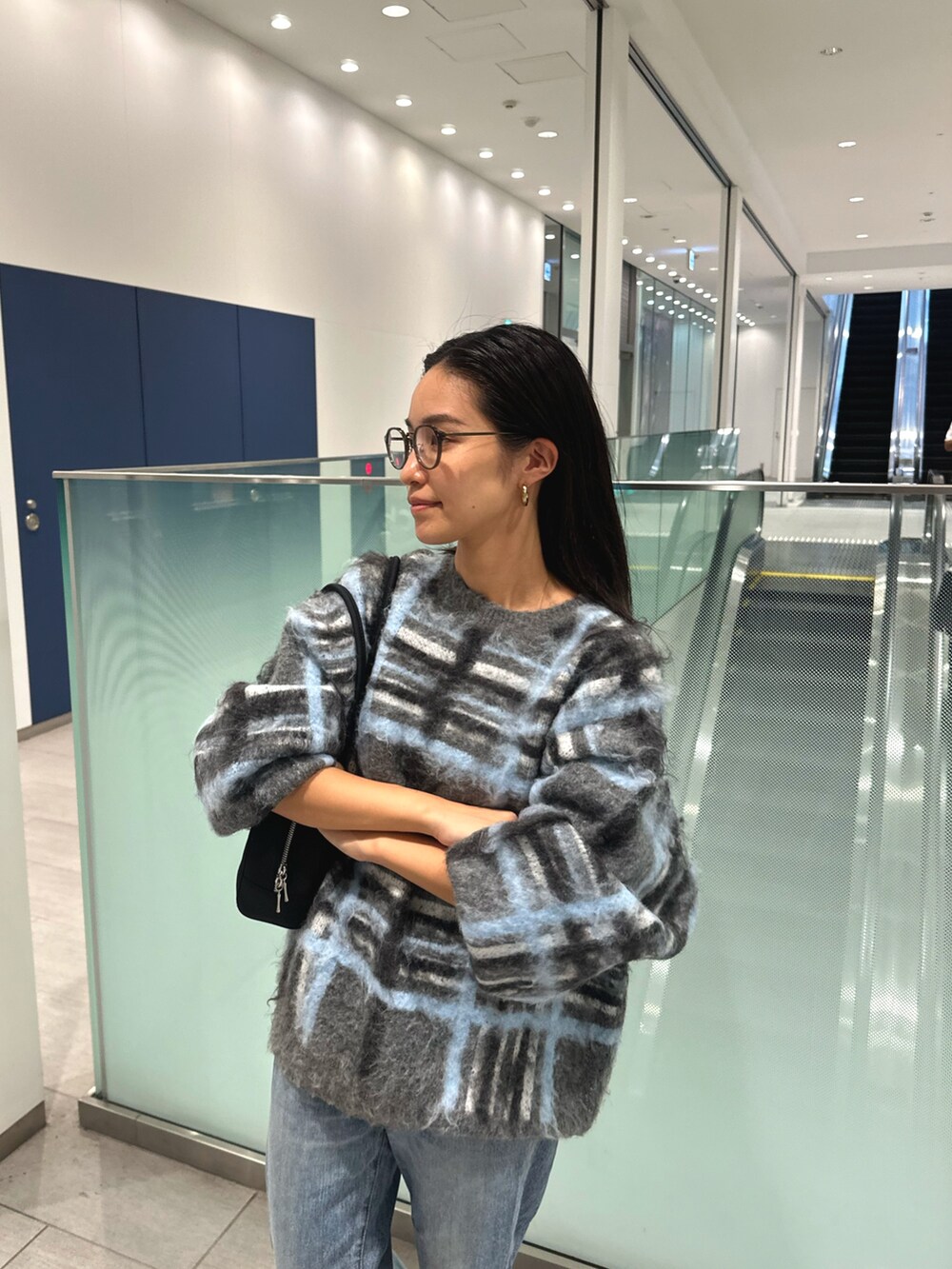 グレー系のニット/セーター、ブルー系のデニムパンツ、ブラック系のハンドバッグを着用したレディースの秋コーディネートの4枚目の写真