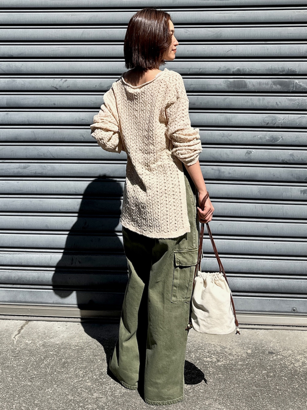 ベージュ系のニット/セーター、グリーン系のカーゴパンツ、ホワイト系のショルダーバッグを着用したレディースの春コーディネートの3枚目の写真