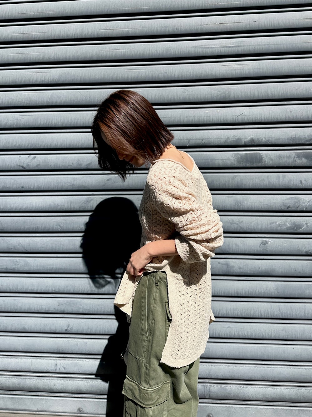 ベージュ系のニット/セーター、グリーン系のカーゴパンツ、ホワイト系のショルダーバッグを着用したレディースの春コーディネートの5枚目の写真