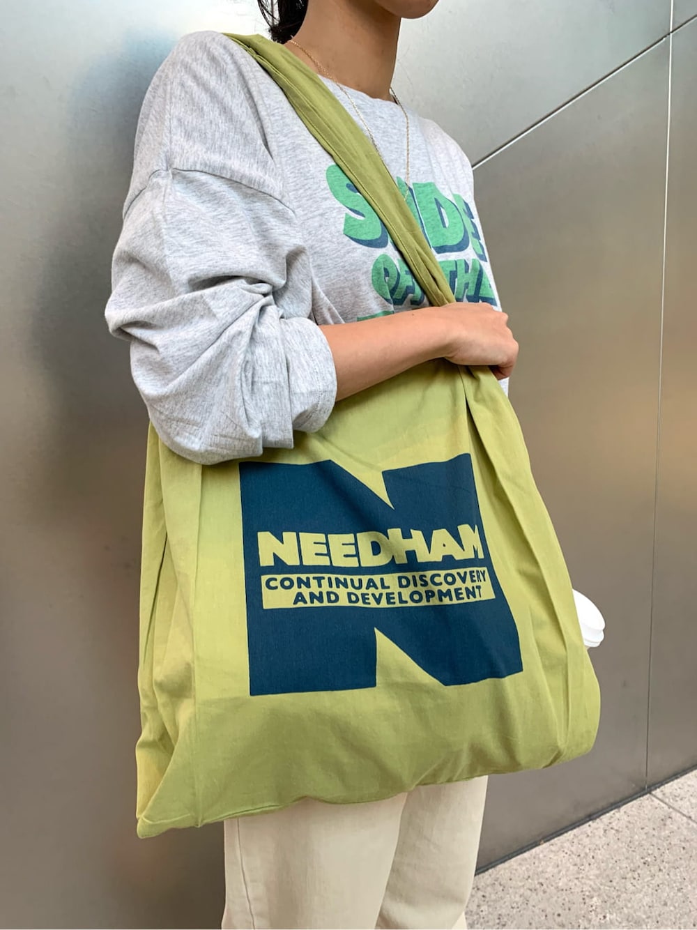 ベージュ系のステンカラーコート、ブラウン系のパンプス、グリーン系のエコバッグ/サブバッグを着用したレディースの冬コーディネートの4枚目の写真