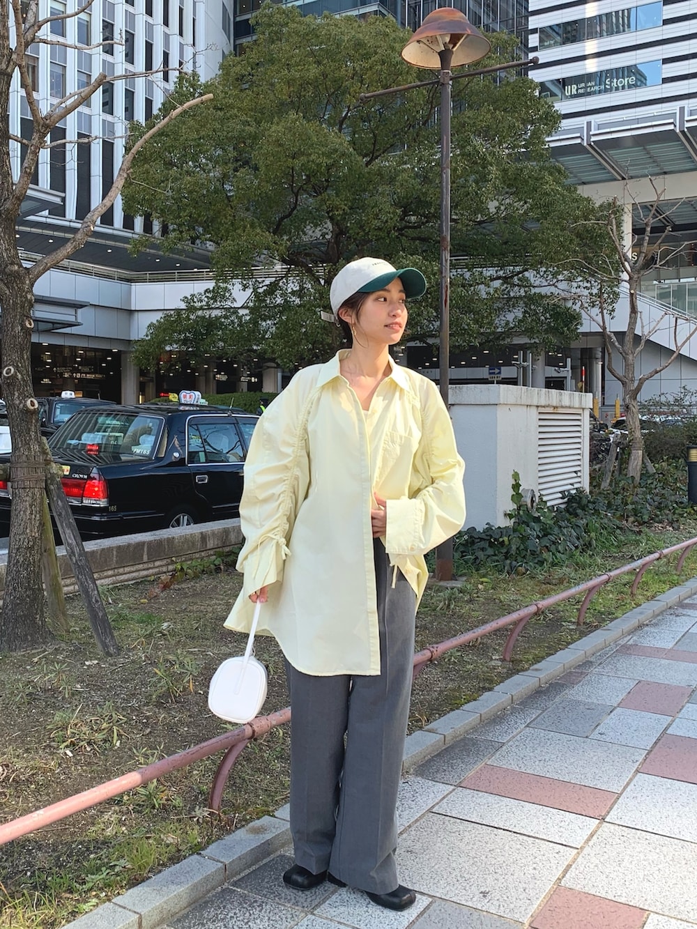 イエロー系のシャツ/ブラウス、グレー系のスラックス、ホワイト系のハンドバッグを着用したレディースの冬コーディネートの2枚目の写真