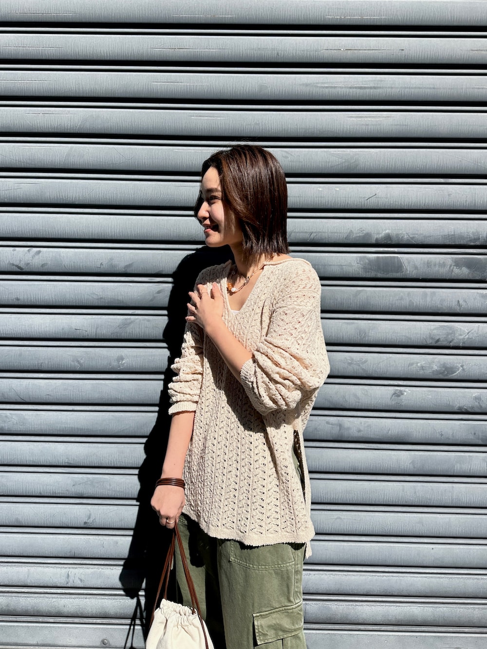 ベージュ系のニット/セーター、グリーン系のカーゴパンツ、ホワイト系のショルダーバッグを着用したレディースの春コーディネートの4枚目の写真