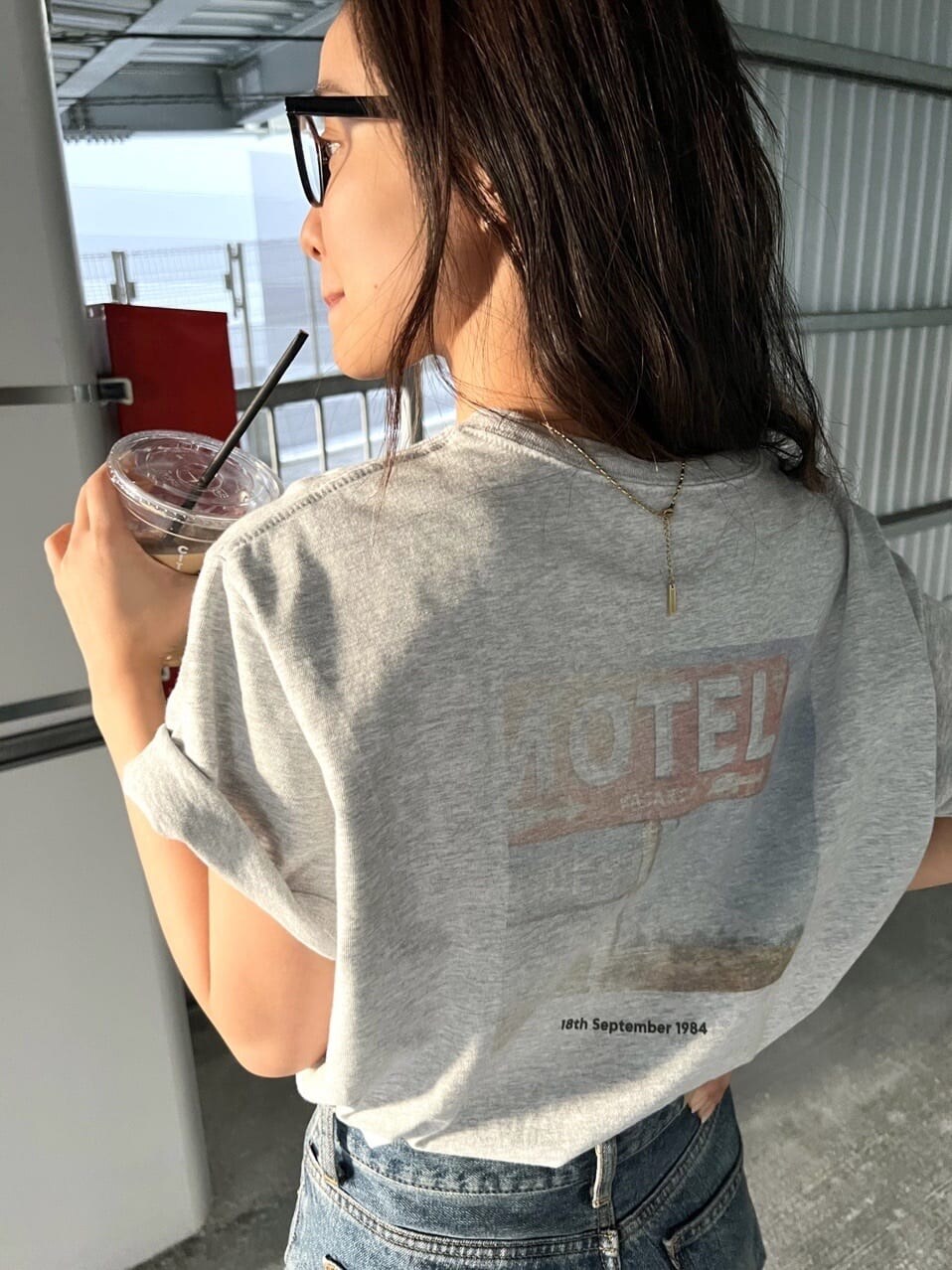 グレー系のTシャツ/カットソー、ブラック系のサンダル、ブルー系のデニムパンツを着用したレディースの春コーディネートの2枚目の写真