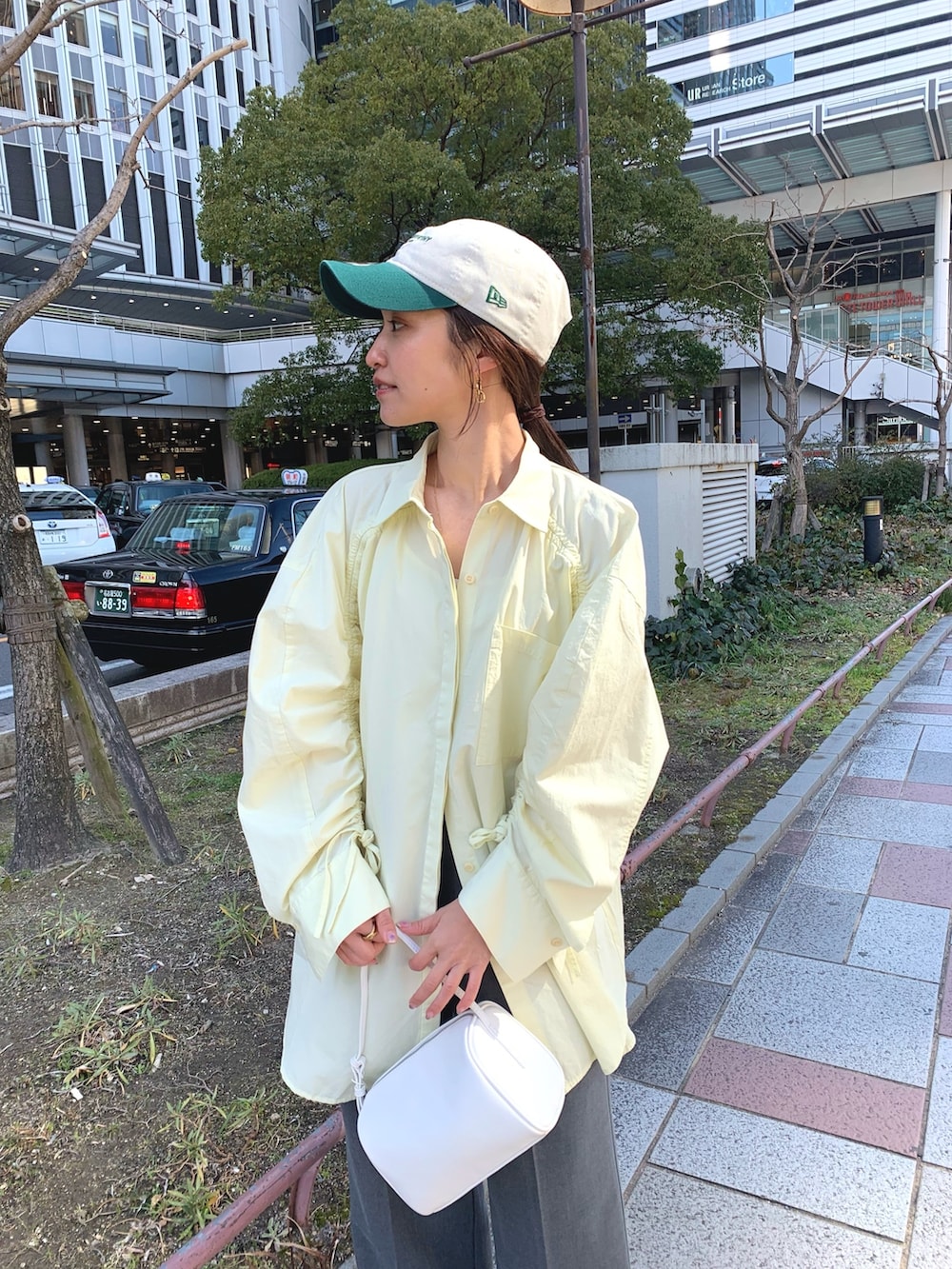 イエロー系のシャツ/ブラウス、グレー系のスラックス、ホワイト系のハンドバッグを着用したレディースの冬コーディネートの3枚目の写真