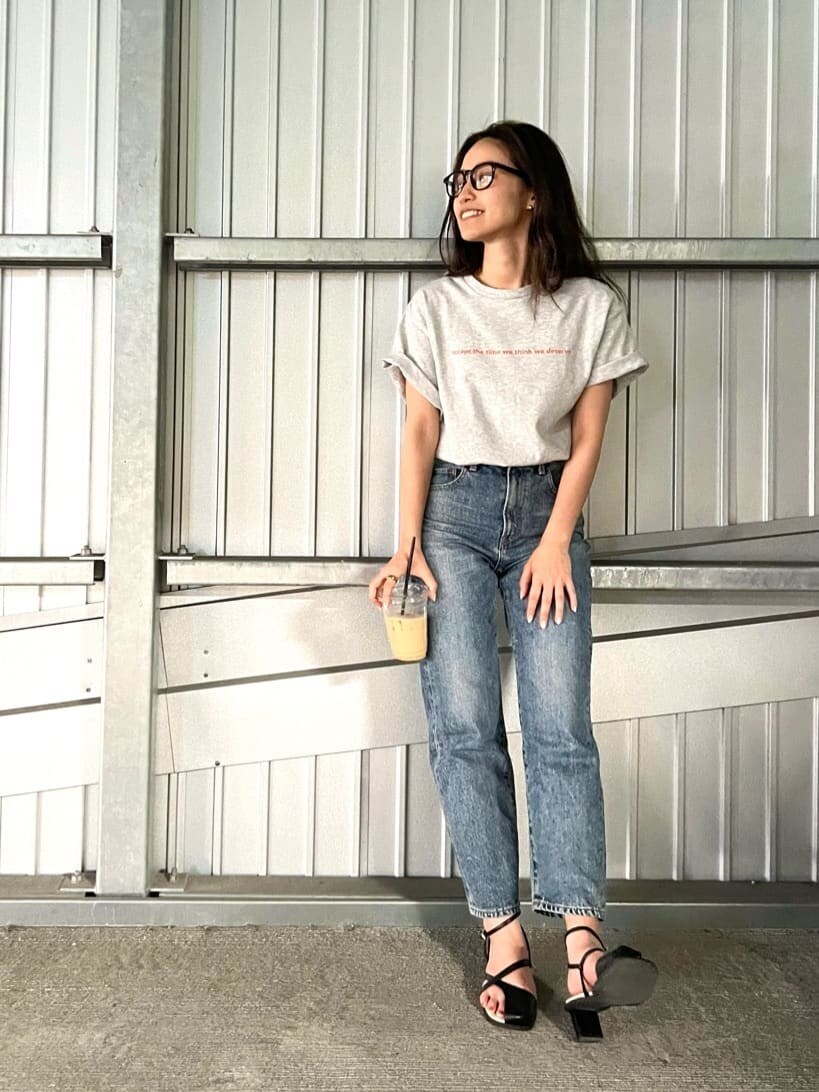 グレー系のTシャツ/カットソー、ブラック系のサンダル、ブルー系のデニムパンツを着用したレディースの春コーディネートの3枚目の写真