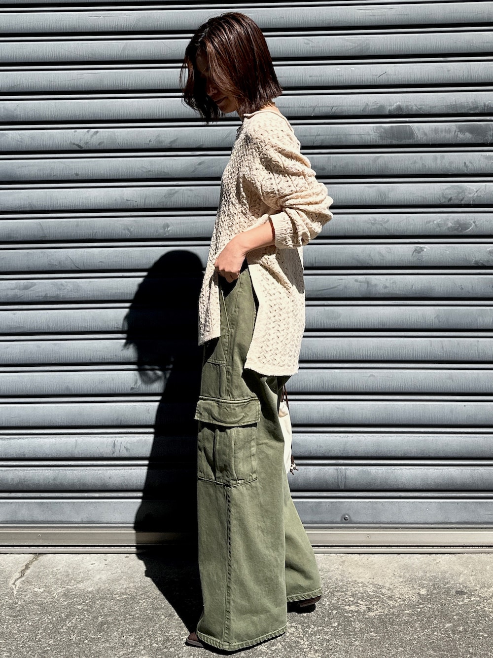 ベージュ系のニット/セーター、グリーン系のカーゴパンツ、ホワイト系のショルダーバッグを着用したレディースの春コーディネートの2枚目の写真