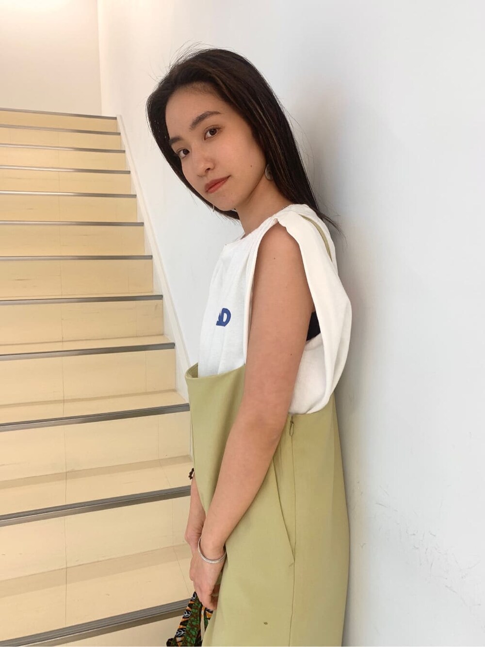 ブラック系のサンダル、ホワイト系のタンクトップ、グリーン系のショルダーバッグを着用したレディースの春コーディネートの6枚目の写真