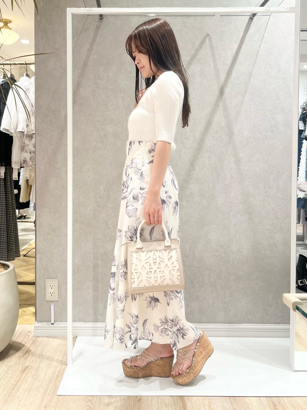 ホワイト系のニット/セーター、グレー系のスカート、ベージュ系のショルダーバッグを着用したレディースの春コーディネートの2枚目の写真