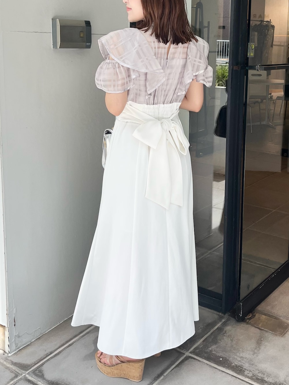 パープル系のワンピース、ブラウン系のサンダル、シルバー系のハンドバッグを着用したレディースの夏コーディネートの3枚目の写真