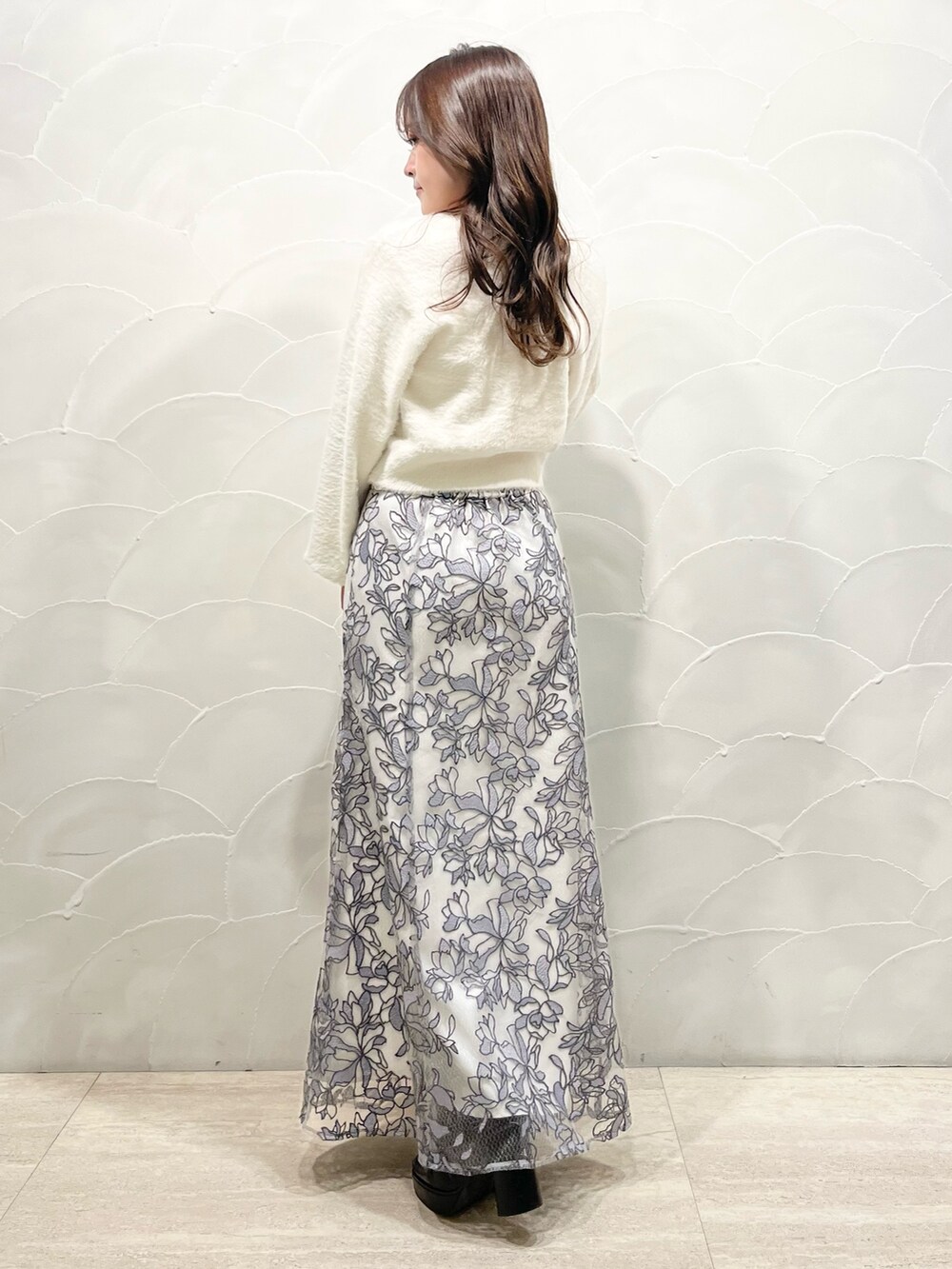 ホワイト系のカーディガン/ボレロ、グレー系のスカート、ブラック系のブーツを着用したレディースの冬コーディネートの3枚目の写真