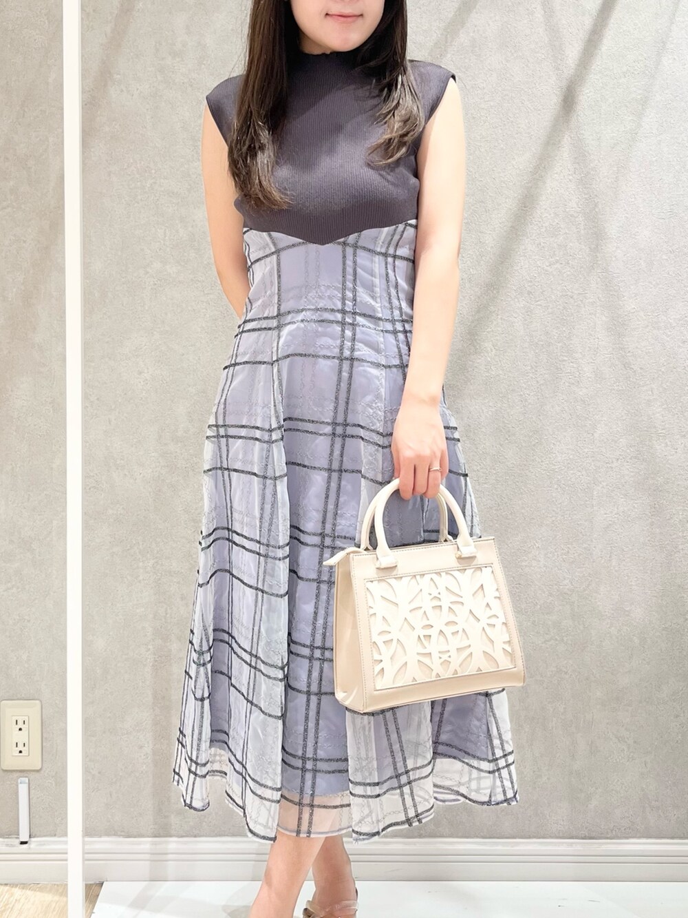 グレー系のワンピース、ベージュ系のショルダーバッグ、ブラウン系のサンダルを着用したレディースの春コーディネートの2枚目の写真