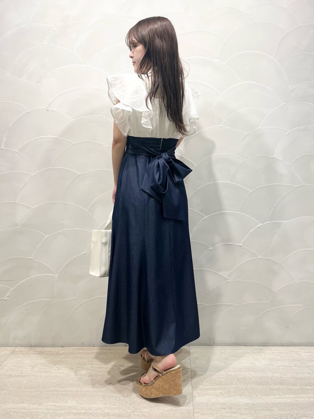 ホワイト系のワンピース、ホワイト系のトートバッグ、ブラウン系のサンダルを着用したレディースの春コーディネートの3枚目の写真