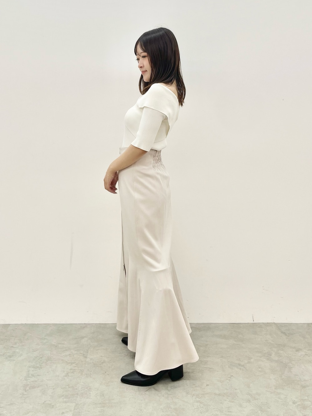 ホワイト系のニット/セーター、グレー系のスカートを着用したレディースの夏コーディネートの2枚目の写真