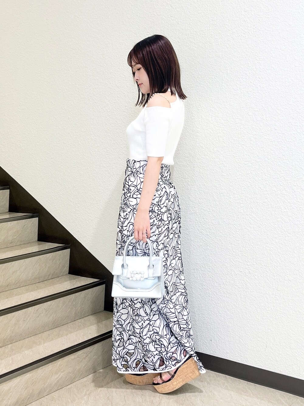 ホワイト系のスカート、ホワイト系のニット/セーター、シルバー系のショルダーバッグを着用したレディースの夏コーディネートの2枚目の写真