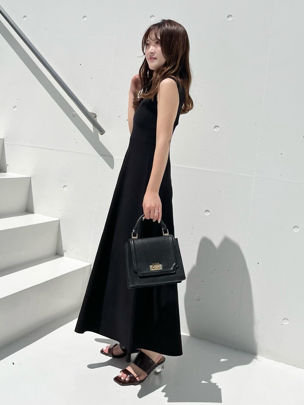 ブラック系のワンピース、ブラウン系のサンダル、ブラック系のハンドバッグを着用したレディースの春コーディネートの5枚目の写真
