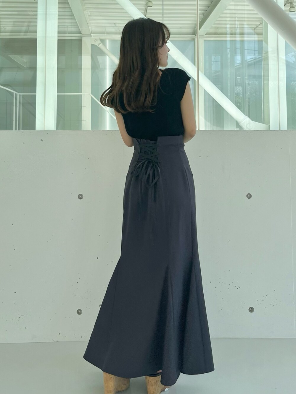 ブラック系のニット/セーター、グレー系のスカート、ブラック系のサンダルを着用したレディースの夏コーディネートの3枚目の写真