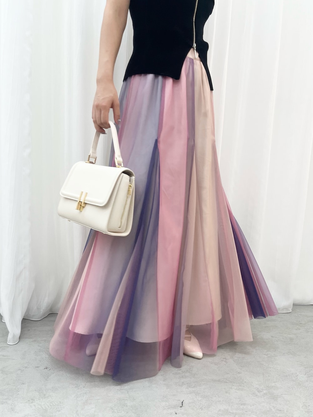 ブラック系のニット/セーター、パープル系のスカート、ベージュ系のパンプスを着用したレディースの夏コーディネートの6枚目の写真