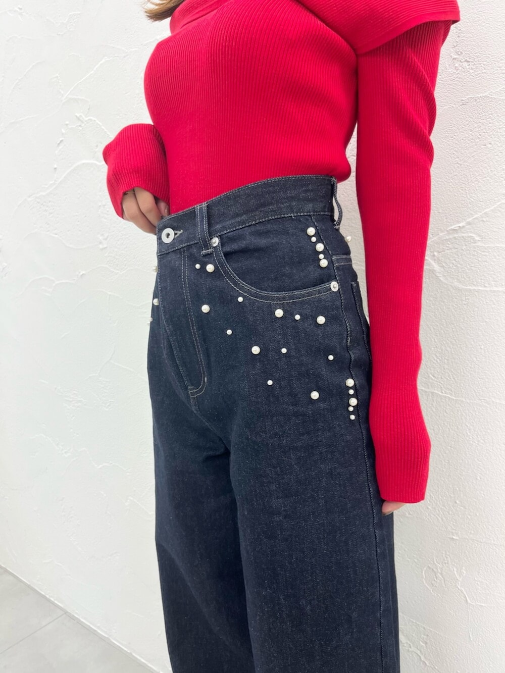 レッド系のニット/セーター、ブルー系のデニムパンツを着用したレディースの秋コーディネートの6枚目の写真