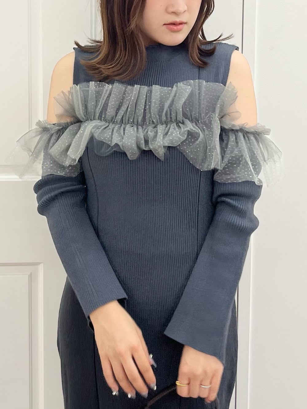 グレー系のワンピース、ブラウン系のハンドバッグ、ブラック系のブーツを着用したレディースの秋コーディネートの4枚目の写真