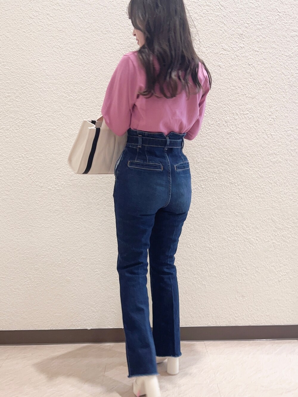 ピンク系のカーディガン/ボレロ、ブルー系のデニムパンツ、ホワイト系のハンドバッグを着用したレディースの冬コーディネートの3枚目の写真